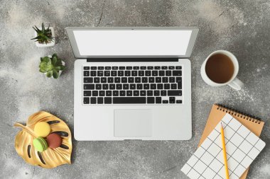 Kırtasiyeli modern dizüstü bilgisayar ve gri arka planda bir fincan kahve.