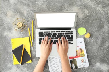 Gri arka planda modern dizüstü bilgisayarı olan kadın elleri