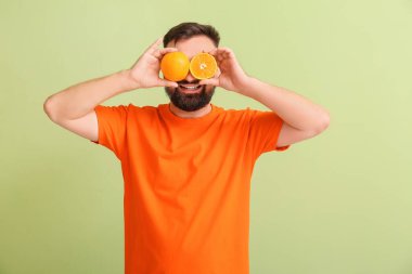 Renkli arka planda portakalları olan komik adam.