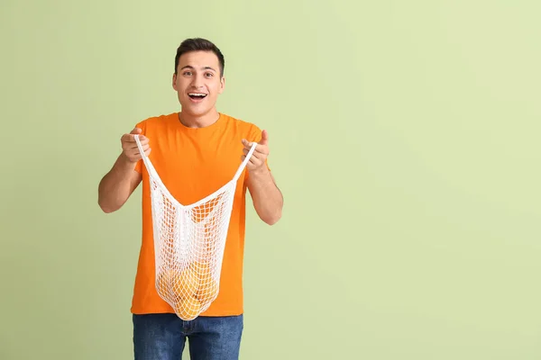 色の背景に熟したオレンジの袋を持つ驚きの男 — ストック写真