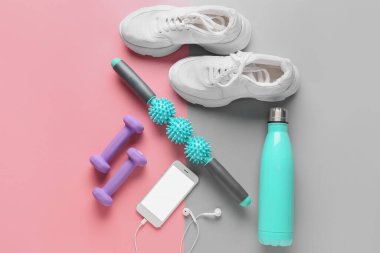 Ayakkabı, dambıl, bir şişe su ve renkli cep telefonu olan vücut silindiri.