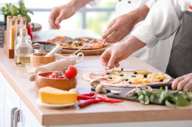 Aşçılar mutfakta lezzetli pizzalar pişiriyor.