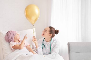 Altın balonlu bir doktor ve klinikte kemoterapi gören küçük bir kız. Çocukluk kanseri farkındalığı