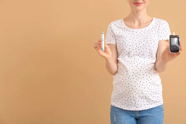 Schwangere Diabetikerin Mit Digitalem Glukometer Und Lanzettstift Auf Farbigem Hintergrund — Stockfoto