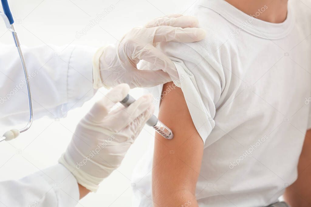 Doctor giving diabetic boy insulin injection in clinic