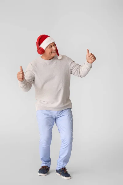 Reifer Mann Hört Weihnachtsmusik Auf Grauem Hintergrund — Stockfoto