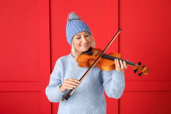 Mature woman with violin on color background