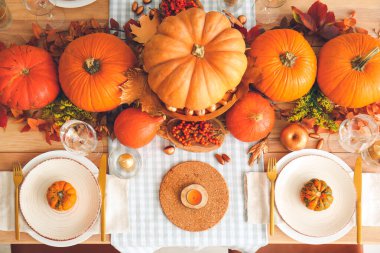Yemek odasında balkabakları ve sonbahar yaprakları olan güzel bir masa.