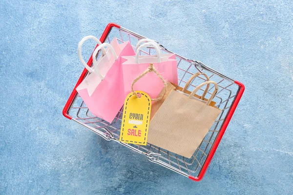 Shopping basket with bags and tag with text CYBER MONDAY SALE on color color