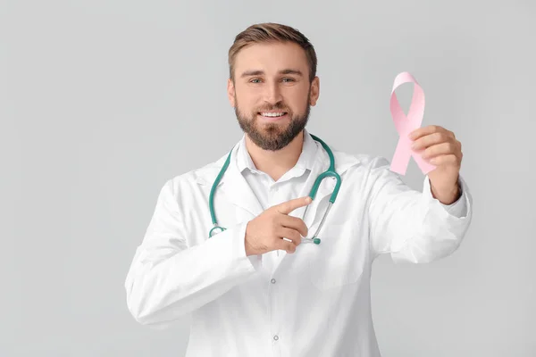 Doctor with pink ribbon on grey background. Breast cancer awareness concept