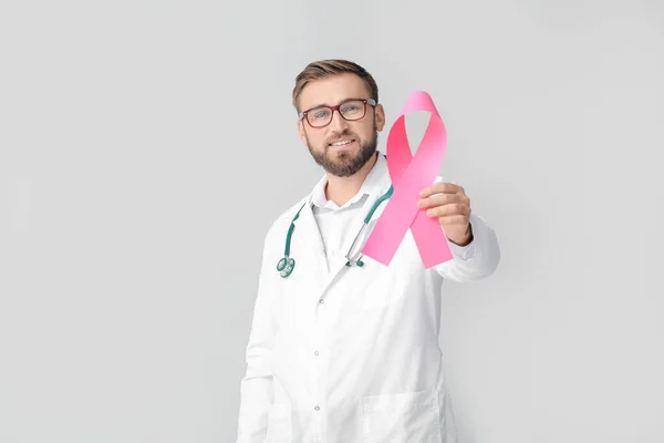 Doctor with pink ribbon on grey background. Breast cancer awareness concept