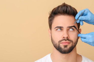 Genç adam renk arkaplanı üzerinde kaş düzeltme prosedüründen geçiyor