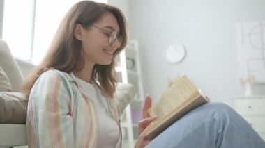 Evde kitap okuyan güzel genç bir kadın.