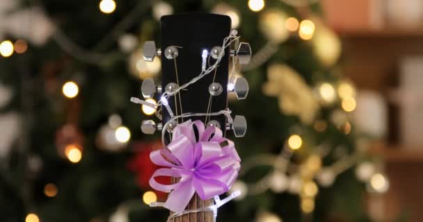 Nahaufnahme Einer Gitarre Mit Leuchtendem Kranz Als Weihnachtsgeschenk — Stockvideo