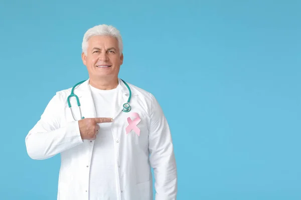 Doctor with pink ribbon on color background. Breast cancer awareness concept