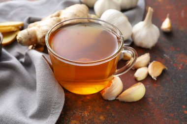 Arka planda bir fincan sağlıklı sarımsaklı çay.