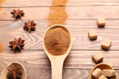 Tahta arka planda tarçın tozu, anason ve şeker ile kaşık