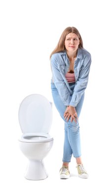 Beyaz arka planda sık sık işeme sorunu olan bir kadın. Diyabet belirtileri