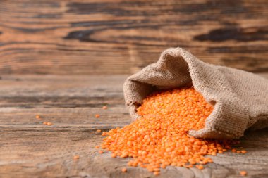 Tahta masada çiğ mercimek dolu çanta.