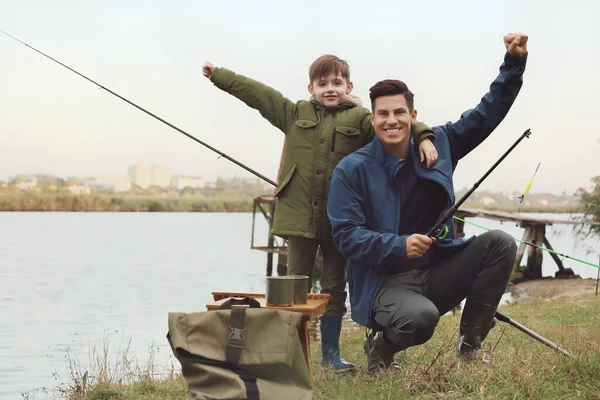 Little boy and his father fishing on river