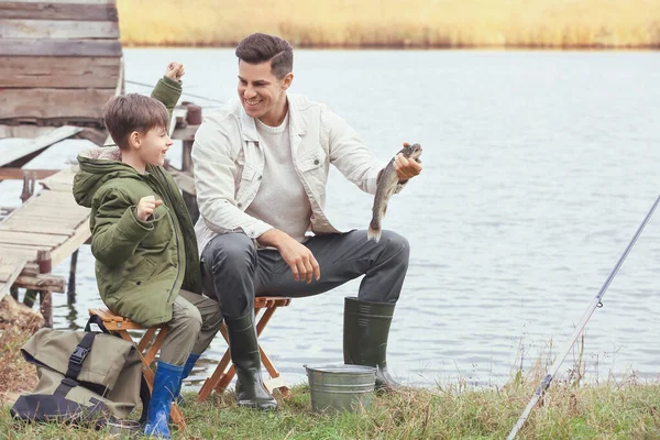 Little boy and his father fishing on river