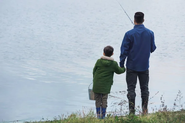 Little boy and his father fishing on river