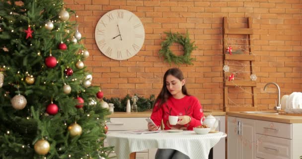 Красивая Молодая Женщина Мобильным Телефоном Пьет Чай Кухне Канун Рождества — стоковое видео