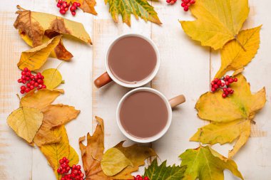 Beyaz ahşap arka planda sonbahar yapraklı sıcak kakao içeceği.