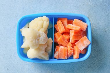 Renkli arka planda farklı donmuş sebzelerle bölünmüş kutu.