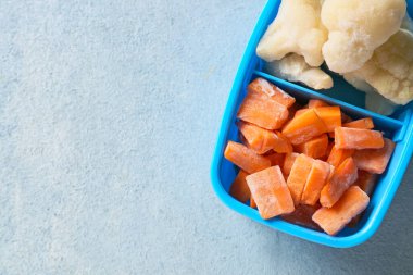 Renkli arka planda farklı donmuş sebzelerle bölünmüş kutu.