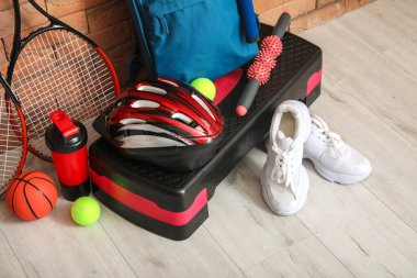 Tuğla duvarın yanında spor aletleri var.