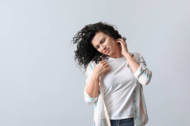 Alerjisi olan genç bir kadın gri arka planda kaşınıyor.