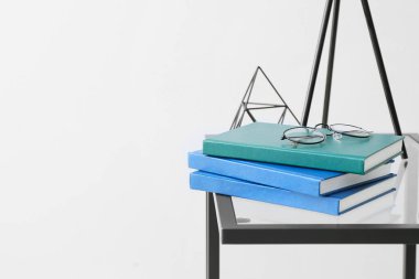 Masada ışık arkaplanı karşısında kitap ve gözlük yığını