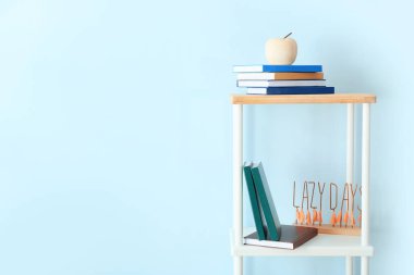 Renk duvarının yanında kitaplı ve dekorlu raf ünitesi