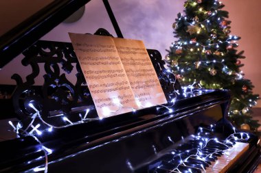Not kağıtları ve Noel dekoru olan büyük piyano.