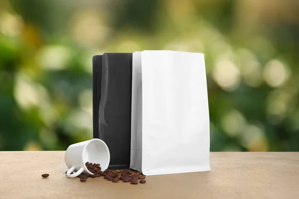 Paper bags for coffee and cup with beans on table outdoors