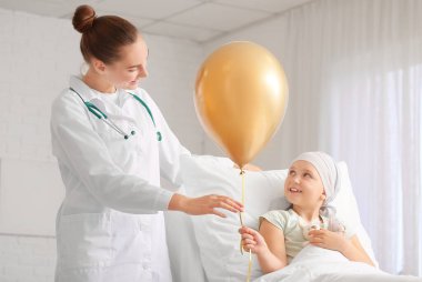 Altın balonlu bir doktor ve klinikte kemoterapi gören küçük bir kız. Çocukluk kanseri farkındalığı