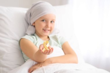 Klinikte altın kurdeleli küçük bir kız. Çocukluk kanseri farkındalığı