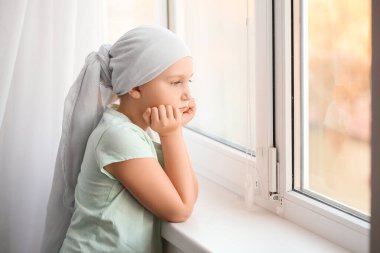 Kemoterapiden sonra kliniğin penceresinin yanında küçük bir kız.