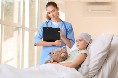 Hemşire ve küçük kız klinikte kemoterapi görüyor.