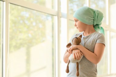 Kemoterapiden sonra kliniğin penceresinin yanında küçük bir kız.