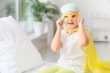 Klinikte süper kahraman kostümü giyen küçük bir kız. Çocukluk kanseri farkındalığı