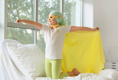 Klinikte süper kahraman kostümü giyen küçük bir kız. Çocukluk kanseri farkındalığı