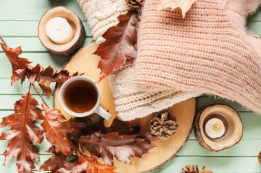 Güz kompozisyonu, şık kıyafetler ve ahşap arka planda bir fincan çay.