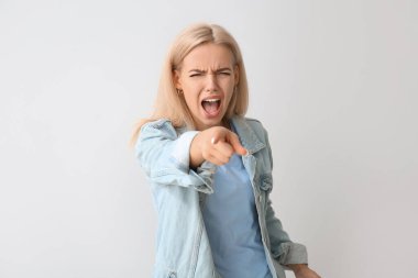 Stresli genç kadın gri arka plandaki izleyiciyi işaret ediyor