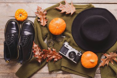 Ahşap arka planda fotoğraf makinesi ve kıyafetlerle güzel bir sonbahar kompozisyonu.