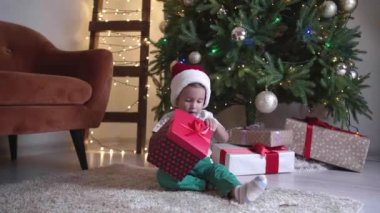 Evde Noel hediyesi olan küçük bir çocuk.