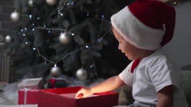 Küçük bebek Noel hediyesini evde açıyor.