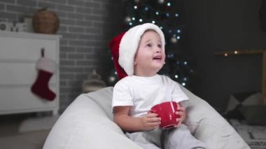 Küçük bebek Noel arifesinde evde sıcak kakao içiyor.