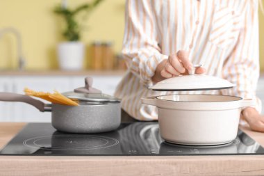 Kadın mutfakta yemek pişiriyor.